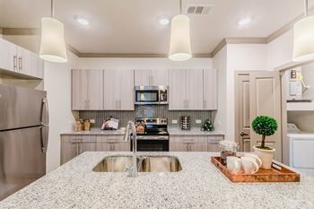 A modern kitchen with a granite countertop and stainless steel appliances.
